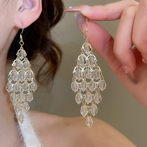 Close-up of elegant gold crystal teardrop fringe earrings with sparkling tassel design