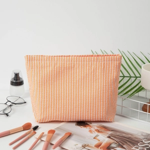 Seersucker cosmetic bag in orange and white vertical stripes for travel storage