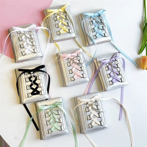 Flat lay of multiple metallic silver PU wallets with colorful balletcore ribbon ties