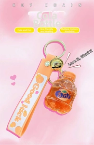 Close-up of creative orange soda bottle keychain with liquid, gold bell and silicone strap