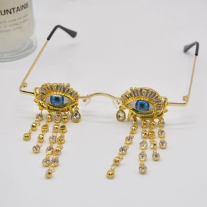 Gold metal eye-shaped sunglasses with blue pupils and sparkling rhinestone tassels