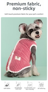 Detail of pink coral fleece dog vest with soft pom-pom trim and embroidered bear patch