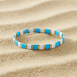 Detail of blue and white Tila bead stretch bracelet on a textured beach sand background