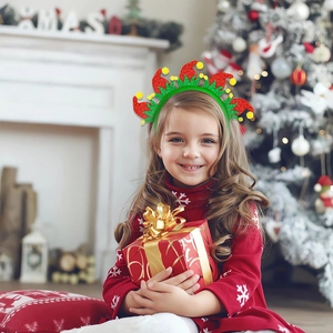 Close-up of a child wearing a green Christmas headband with glittery elf hat decorations