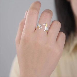 Dettaglio ravvicinato di un anello a forma di bassotto bicolore argento e oro sulla mano
