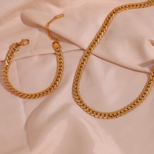 Macro view of 18K gold plated Cuban chain necklace and bracelet set on silk fabric