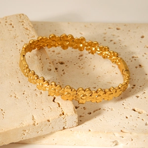 18K gold plated stainless steel daisy flower open cuff bracelet on beige stone background