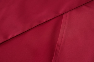 Close-up of deep red evening dress fabric showing fine stitching and smooth texture
