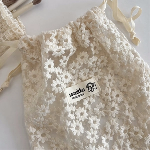 Close-up of cream mesh lace drawstring bag with delicate daisy embroidery detail