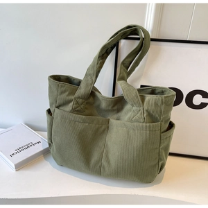 Détail du sac cabas en velours côtelé vert avec deux poches avant et texture douce