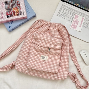 Detailed close-up of pink plaid quilted backpack featuring front zipper pocket and logo