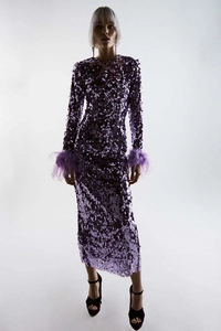 Close-up of purple sequin fabric with ostrich feather cuffs on the long sleeve dress