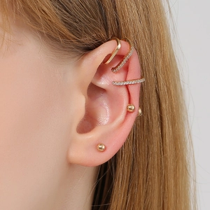 Three gold geometric ear cuffs and studs set with cubic zirconia on a female ear