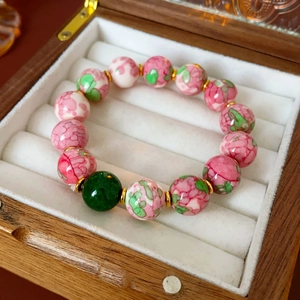Detail of colorful floral ceramic bead bracelet with gold spacers in a wooden gift box