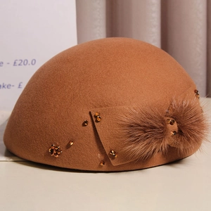 Detail of caramel wool beret featuring a mink fur bow and antique copper beads decoration