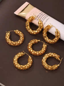Detailed view of three pairs of gold textured scale hoop earrings in 18K plated steel