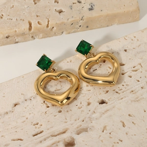 Golden heart earrings with green square zircon charms on a textured stone base