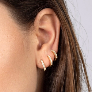 Three gold micro-pave cubic zirconia hoop earrings shown on ear for a luxury layered look