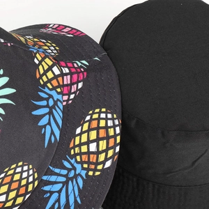 Detailed view of canvas bucket hat featuring colorful pineapple print and black fabric texture