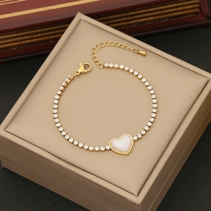 Macro detail of a golden heart pendant bracelet with white inlay on a jewelry box