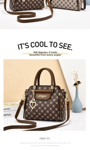 Detail of the brown monogram tote bag with gold lettering and heart pearl pendant charm
