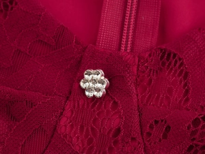 Détail macro de robe en dentelle rouge avec bijou fleur en strass et fermeture éclair assortie