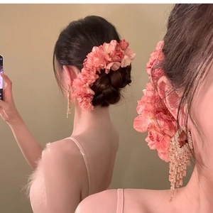 Detail of pink layered floral hairpin with elegant gold fringe tassel drop earrings