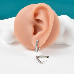 Close-up of silver V-shaped hoop earrings featuring vintage engraved curved textures