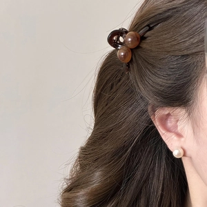 Close-up of a woman wearing a small amber round bead hair claw clip for a side hairstyle