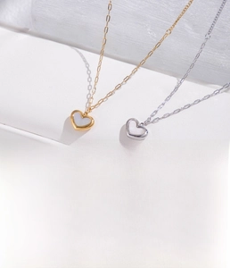 Macro detail of gold and silver heart necklaces with mother of pearl and zircon inlays