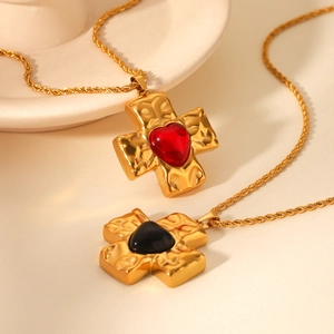 Detail of cross pendants with hammered texture and red or black heart stones on twist chains