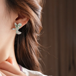 Detail of flower stud earrings with green petals and opal center on model ear
