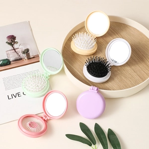 Colorful mini folding hair brushes with mirrors on a wooden tray for travel and style