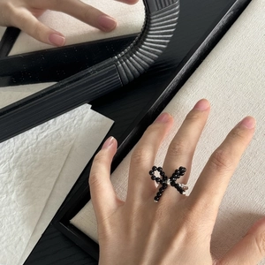 Detail of beaded bow ring with black beads and silver accents worn on hand