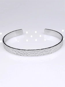Macro detail of silver stainless steel open bangle with textured geometric crackle finish