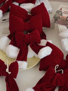 Detail of red velvet Christmas bows with white faux fur pom-poms on a festive table