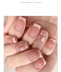 Close-up of French tip press-on nails with 3D pink floral and butterfly accents