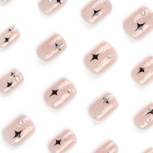 Short square pink glitter press-on nails featuring black star patterns and silver rhinestones