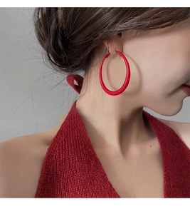 Close-up of model wearing large matte red hoop earrings with minimalist stylish design