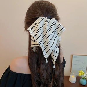 Détail d'une pince à cheveux à nœud rayé avec des perles gouttes élégantes