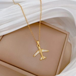 Elegant gold airplane pendant necklace with crystal wings on beige jewelry box display