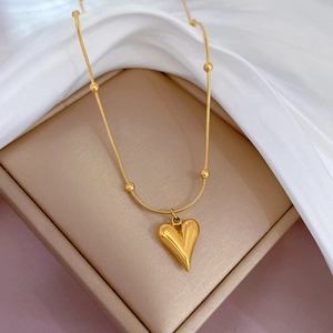 Close-up of 18k gold plated heart pendant necklace on luxury champagne silk display