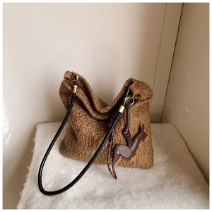 Close-up of brown faux fur tote bag with black leather straps and dog charm