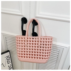 Detailed view of pink woven jelly basket bag hanging on a door handle for daily travel