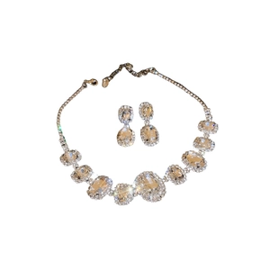 Elegant silver oval necklace and earrings set with sparkling crystals on white background