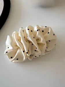 Detail of elegant cream polka dot satin hair clip with pleated texture and smooth finish