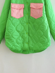 Dettaglio giacca trapuntata verde neon con tasche rosa e bottoni automatici in metallo