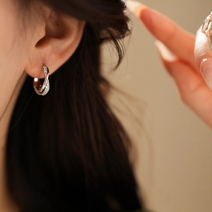 Close-up of twisted silver hoop earrings with cubic zirconia stones worn by model