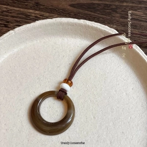 Macro detail of agate circle pendant on woven brown cord with decorative beads