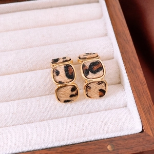 Macro shot of 18K gold plated square earrings with leopard print fabric inlay